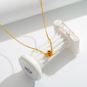 Collana dorata con ciondolo a rosa 3D esposta su un piedistallo a colonna greca bianca