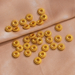 Macro view of golden stainless steel wheel spacers on silk fabric for DIY jewelry making