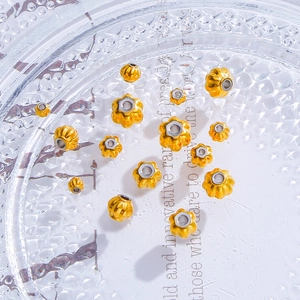 Golden pumpkin beads and flower spacers for DIY jewelry making in a decorative glass tray