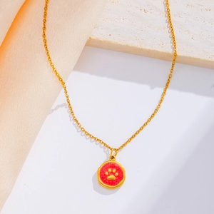 Detail view of a 18k gold plated pet paw pendant with red enamel on a delicate cross chain