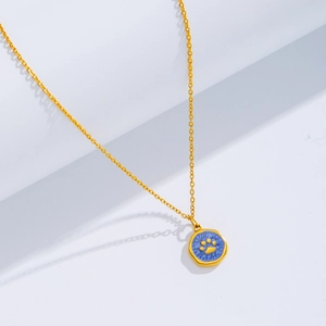 Detail of 18k gold plated necklace featuring a blue round pendant with a gold paw print