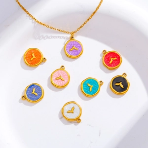 Detail view of colorful round enamel pendants with gold bird wings on a white plate