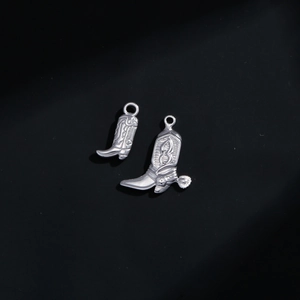 Silver western cowboy boot charms with spur details and floral engraving on black background