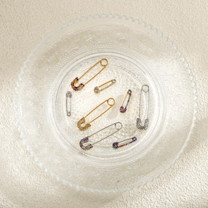 Macro detail of multicolored rhinestone safety pins in gold and silver finish