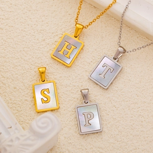 Détail de pendentifs lettres en nacre irisée avec finitions dorées et argentées élégantes