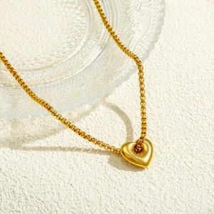 Elegant gold heart pendant necklace with polished box chain on minimalist textured background
