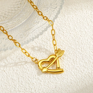 Stainless steel 18K gold heart and arrow pendant necklace on textured background