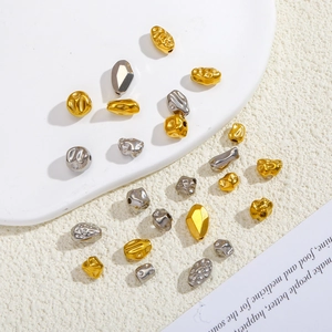 Primo piano di perle in acciaio inossidabile oro e argento con trame martellate e sfaccettate