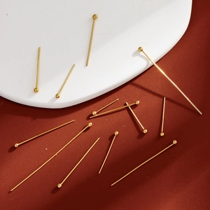 Detailed close-up of golden ball head pins for jewelry making in various sizes