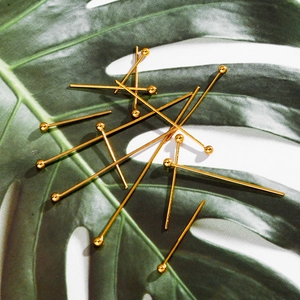 Close-up of polished gold-plated ball head pins on leaf for DIY jewelry making