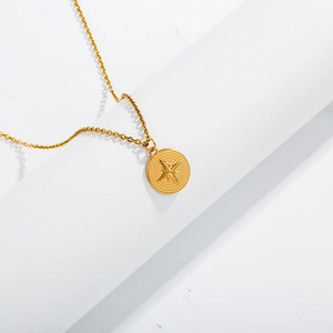Polished gold stainless steel necklace with round eight-pointed star pendant on white blocks