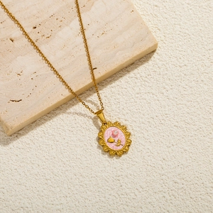 Detailopname van vintage gouden hanger met roze reliëfroos en een subtiele parel