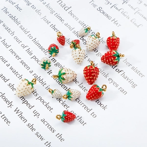 Detailed close-up of red and white 3D strawberry charms on vintage book pages