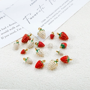 Detailed macro view of red and white 3D strawberry pendants with gold rings for DIY crafts