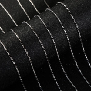 Detailed close-up of silver box chain link texture on a black jewelry display stand
