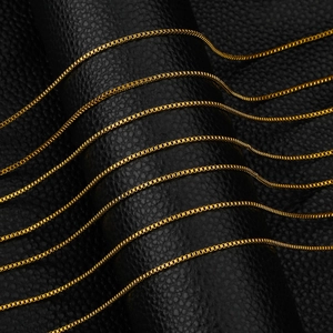 Polished 1.5mm gold box chains displayed on black leather stand for jewelry making