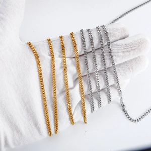 Plusieurs colliers à mailles gourmettes en acier doré et argenté sur une main gantée
