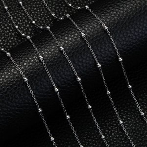 Silver stainless steel bead chain with oval links on textured black leather surface