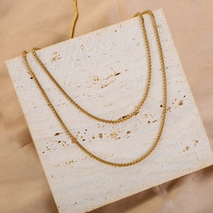 Detail view of 1.8mm golden stainless steel box chain on a textured stone display board