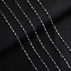 Detailed close-up of polished silver twisted water wave chain links on black leather texture