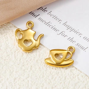 Macro detail of gold-plated teapot and teacup charms with heart cutout for DIY jewelry