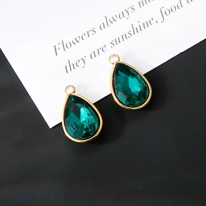 Detailed view of emerald green teardrop glass pendants with 18K gold plated metal edges