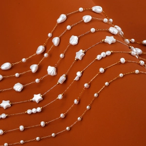 Layered gold chain necklace with white pearls and celestial star shell charms