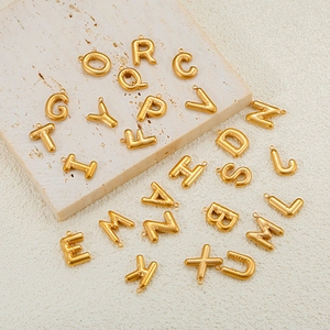 Macro shot of gold-plated balloon style alphabet charms with a shiny 3D metallic texture