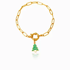Detail of golden paperclip bracelet with a green enamel Christmas tree charm and round clasp