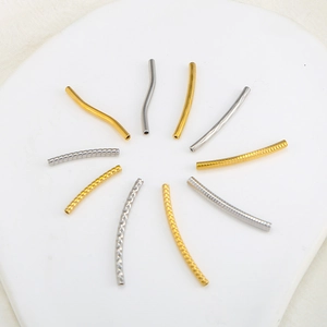 Dettaglio macro di perline a tubo curvo in oro 18K e argento con finiture lisce e zigrinate