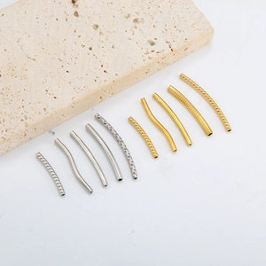 Dettaglio macro di tubi distanziatori curvi in oro 18K e argento con motivi per gioielli fai-da-te