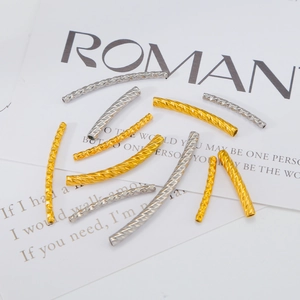Macro shot of gold and silver curved spacer tubes with diamond-cut texture for DIY jewelry