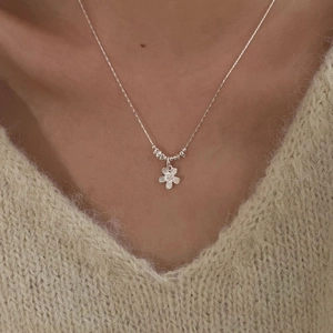 Close-up of s925 silver flower pendant on model wearing a soft beige knitted sweater