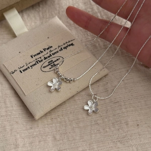 Detailed macro view of S925 sterling silver flower necklaces with a cotton jewelry pouch