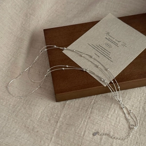 Detail shot of a double-layered S925 silver snake chain with beads on a wooden background