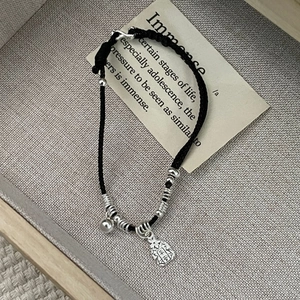 Close-up of s925 silver Ping An charm on a black woven cord bracelet with silver beads