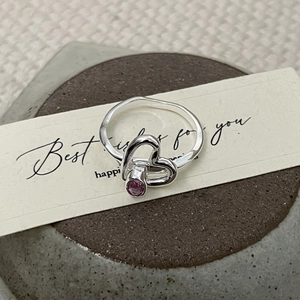 Détail d'une bague en argent S925 avec zircon rose et design creux à double cœur