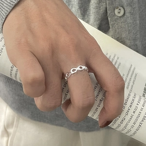 Macro view of minimalist hollow oval chain ring in polished silver on a neutral background