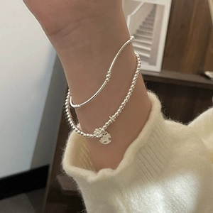 Close-up of s925 silver beaded bracelet set with flower charms on woman wearing sweater