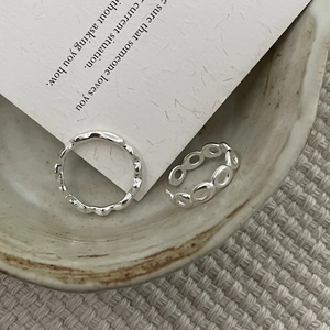 Détail de bagues en argent sterling s925 ondulées et évidées sur une plaque céramique