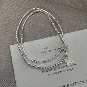 Close-up of double-layer S925 silver beaded bracelet with rocking horse and flower charm