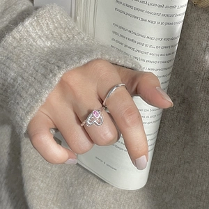 Gros plan d'une bague coeur en argent S925 avec zircon rose portée avec un anneau fin