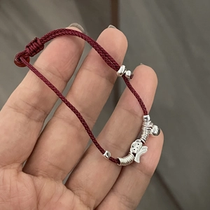 Detail view of 925 silver elephant charm on a red braided rope bracelet with adjustable cord