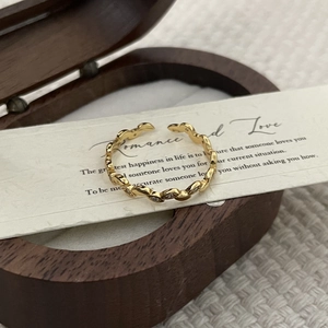 Detailed close-up of a gold wavy olive branch ring with tiny zircon stones on paper