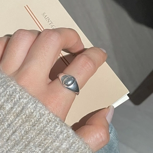 Primo piano di un anello ovale minimalista in argento sterling S925 indossato con un maglione