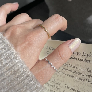 Detail of silver and gold olive leaf rings with zircons on vintage paper background