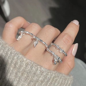 Close-up of S925 sterling silver beaded rings with heart charms on hand with sweater