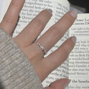 Detail of S925 silver olive branch ring with tiny zircons worn with a beige sweater