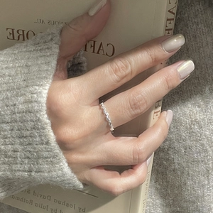 Detail of silver olive branch ring on model hand holding a book in warm light