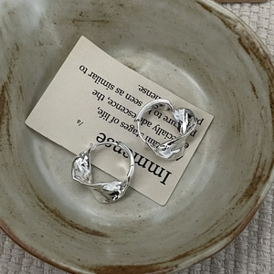 Detail of S925 silver earrings with irregular lava texture on vintage paper and fabric